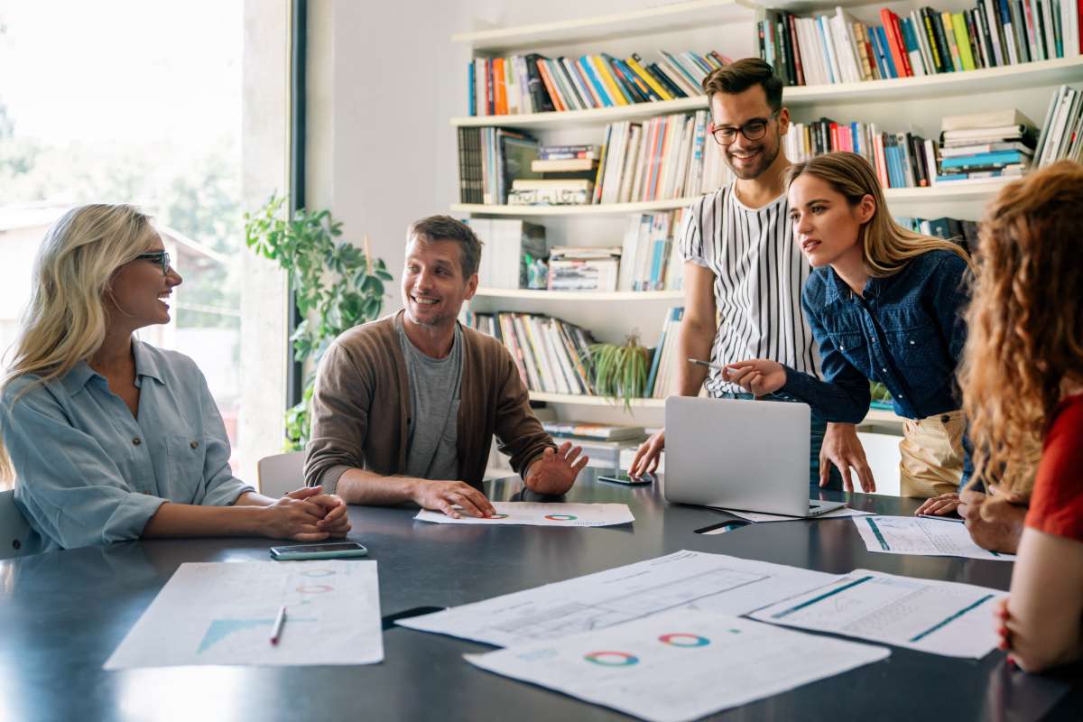 A group of coworkers around a table that has charts on it.